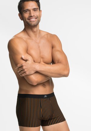 Boxer-briefs rayés noir et orange avec une ceinture noire, fabriqués en tissu doux, dotés d'un ajustement près du corps et de coutures minimales pour plus de confort.