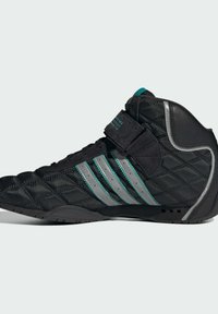 Čierna atletická obuv s prešívanou textúrou, striebornými a teal akcentmi, vystuženou pätou a suchým zipsom. Obsahuje gumovú podrážku pre lepšiu trakciu.