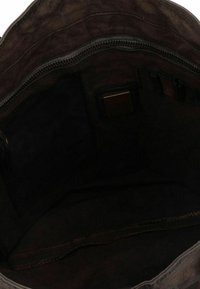 Interior de bolsa de tela marrón con cierre de cremallera, bolsillos y compartimentos. Textura suave con detalle de costura en contraste.