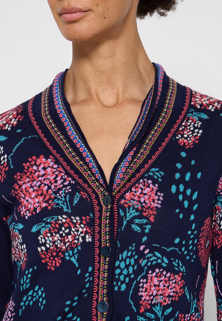 Cardigan navy con motivo floreale in rosa e turchese, con apertura a bottoni e colletto in fantasia colorata. Tessuto lavorato morbido.