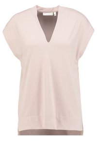 Ljusrosa kortärmad topp med V-krage, mjuk textur, avslappnad passform och sidoklyftor i nederkanten för ökad rörlighet och komfort.