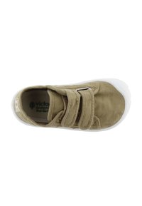Zapato de tela beige con suela de goma blanca, que cuenta con dos correas de velcro. El diseño incluye detalles de costura sutil y una punta redondeada.