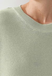Hellgrüner gestrickter Pullover mit einer strukturierten Webart und einem gerippten Kragen, der ein weiches, lockeres Design zeigt.