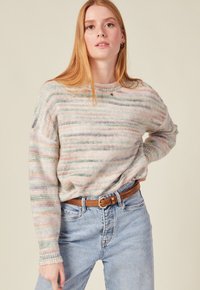 Mehrfarbiger Strickpullover mit horizontalen Streifen in pastellfarbenen Tönen, rundem Halsausschnitt und lockerer Passform, kombiniert mit hellblauen Jeans und einem braunen Gürtel.