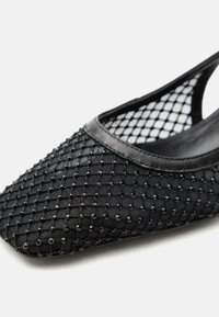 Μαύρο επίπεδο παπούτσι από δίχτυ με μυτερή μύτη, διακοσμημένο με μικρές μαύρες χάντρες και περιμετρικά με λείο μαύρο υλικό.