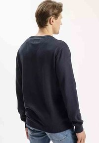 Ciemnogranatowy sweter pulower z okrągłym dekoltem, z prążkowanymi mankietami i dołem, wykonany z miękkiego materiału dzianinowego, przedstawiony z tyłu.