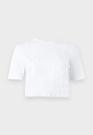 Λευκό crop top με κοντά μανίκια και περίτεχνη δαντέλα με λουλουδένια και γεωμετρικά σχέδια στο μπροστινό μέρος και στα ραντάκια.