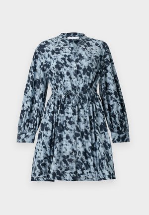 Robe à manches courtes dans un motif tie-dye bleu et blanc, avec une taille élastique et un col, associée à un petit sac à main noir.