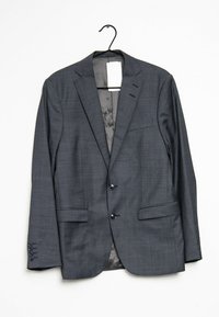 Šedý blazer z textilního materiálu, se dvěma předními kapsami, zapínáním na tři knoflíky a hladkou podšívkou. Visí na háčku.
