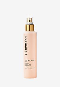 Flacone spray trasparente contenente un tonico rosa chiaro. Presenta un tappo e un'etichetta dorati con testo nero. Design semplice e moderno, adatto per l'uso nella cura della pelle.
