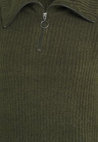Olivengrøn zipped sweater med ribbet tekstur, med høj krave og metal lynlås. Blødt stof med let glans.
