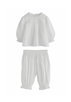 Weiße Bluse mit langen Ärmeln, Biesen- und Spitzendetails, kombiniert mit passenden, elastischen Bundhose mit gerafftem Saum und verkürzter Länge.