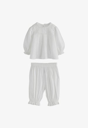 Weiße Bluse mit langen Ärmeln, Biesen- und Spitzendetails, kombiniert mit passenden, elastischen Bundhose mit gerafftem Saum und verkürzter Länge.