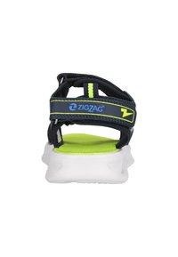 Laivansinis sandaali neonvihreillä yksityiskohdilla, säädettävät remmit ja teksturoitu pohjallinen. Varustettu pehmeällä valkoisella ulkopohjalla tuen antamiseksi.