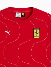 Rød Puma Ferrari T-shirt med bølgede hvide stikninger, Puma-logo på venstre bryst og Ferrari-skjold logo på højre bryst.