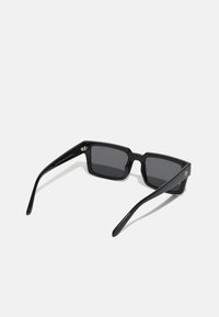 Ochelari de soare rectangulari negri cu lentile întunecate. Fabricat din plastic lucios. Are brațe groase cu un branding subtil pe o parte.