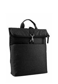 Mochila de tela negra con solapa plegable, cierre de cremallera, bolsillo frontal y un asa en la parte superior. Superficie texturizada y diseño minimalista.