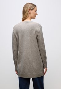 Beżowy sweter dzianinowy z długimi rękawami, ribbowanym dołem i luźnym krojem, prezentujący gładką fakturę i prosty design.