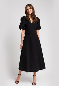 Czarna, sięgająca do kolan sukienka z bufkami, dekoltem w kształcie litery V, dopasowaną talią i zwiewnym dołem. Gładki materiał z minimalnymi detalami i bez widocznych wzorów.