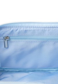 Lys blå stoffpose med glidelås på toppen og en mindre glidelåslomme innvendig. Glatt tekstur og rene sømmer langs kantene.