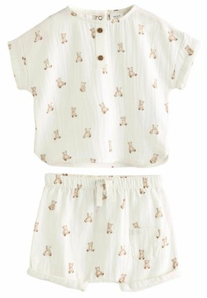 Zweiteiliges Baumwoll-Outfit in Hellcreme, bestehend aus einem kurzärmeligen Oberteil mit Knopfleiste und passenden Shorts, die beide mit Bärenmotiven verziert sind.