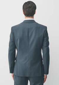 Dunkelblazer aus strukturierter Verarbeitung, mit leichtem Schlitz und knöpfbaren Manschetten. Glattes Material mit subtiler Schimmer und taillierter Passform.
