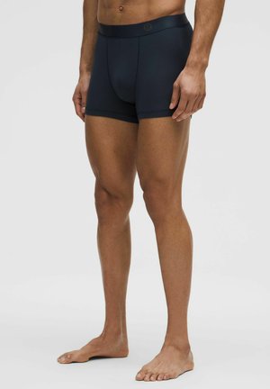 Tumši zilie vīriešu bokseršorti ar gludu, elastīgu jostasvietu un pieguļošu dizainu, izgatavoti no mīksta, elpojoša materiāla. Nav redzamu rakstu vai logo.