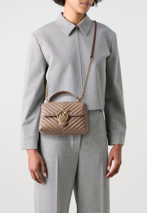 Borsa a tracolla in pelle beige trapuntata, con chiusura in metallo dorato e catena, dotata di una forma strutturata e manico superiore.