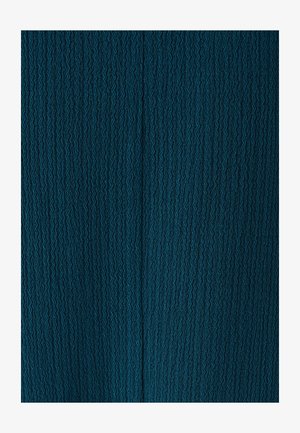 Tela verde azulado con un patrón de zigzag texturizado, que se asemeja a olas. La superficie tiene un ligero relieve, creando profundidad e interés visual.