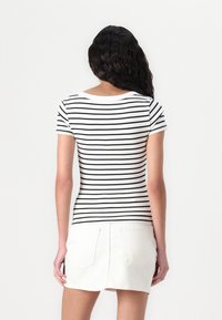 Kortermet, tettsittende topp med svart og hvit horisontalstriping, laget av en myk bomullsblanding. Stil med rund hals.
