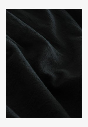 Melna auduma ar mīkstu, teksturētu virsmu, kurā redzamas maigas krokas un gluda apdare. Materiāls uzsver dziļu krāsu.