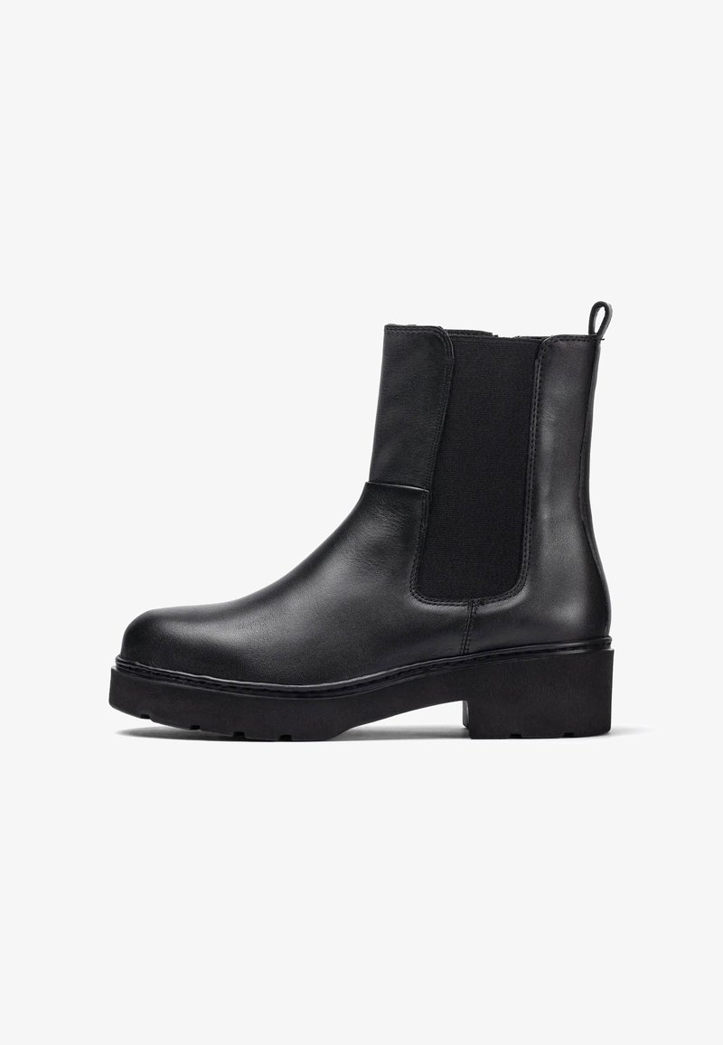 Stivale alla caviglia in pelle nera con pannelli laterali elastici, punta arrotondata, linguetta e suola in gomma spessa. Superficie liscia con cuciture minime.