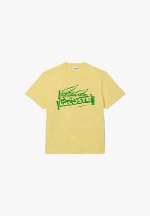 T- shirt in cotone giallo con logo di un coccodrillo verde e il testo "LACOSTE", con un semplice collo rotondo e maniche corte.