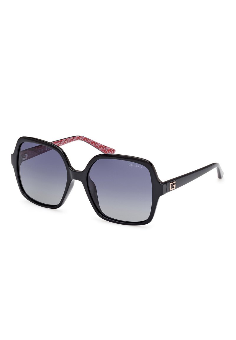 Occhiali da sole neri oversize con lenti sfumate e un design geometrico. Accenti sulle aste a motivo rosso con dettaglio del logo.