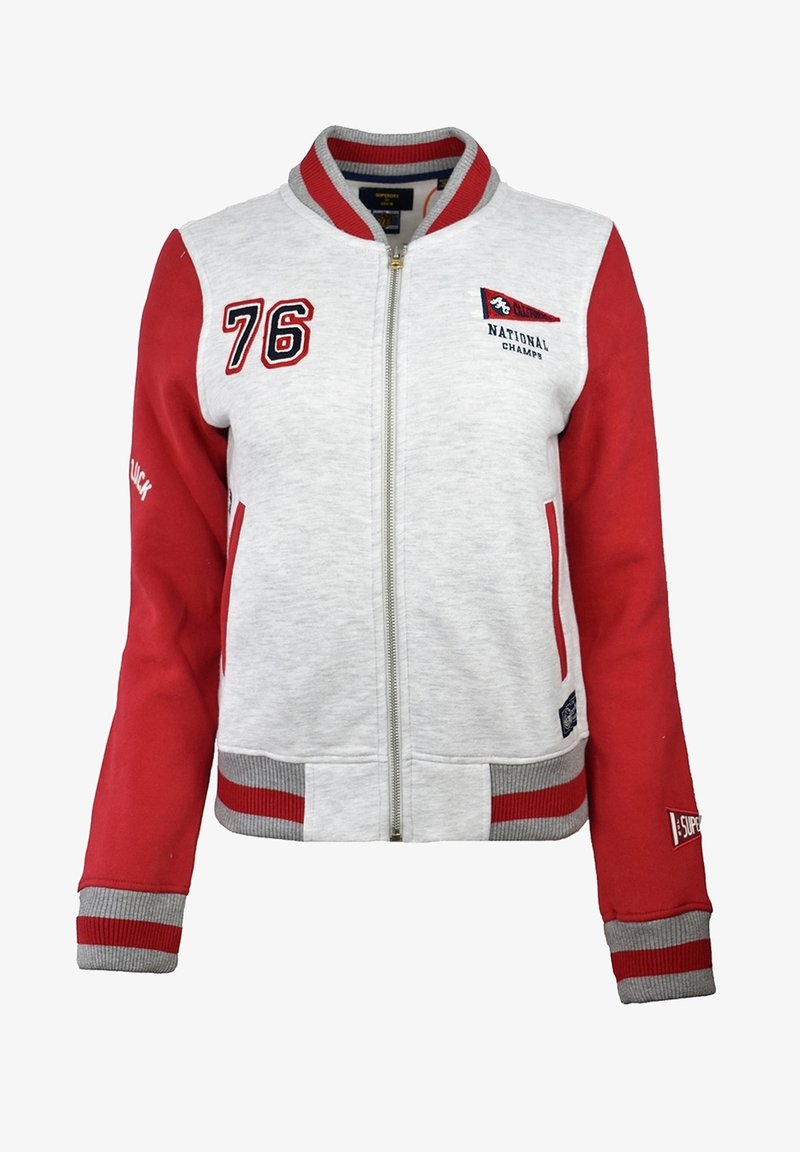 Veste universitaire gris clair et rouge avec fermeture éclair, numéro 76 sur la poitrine, texte "National Champs", et col, poignets et ourlet rayés.