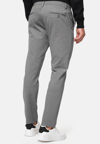 Pantalones grises ajustados con un tejido texturizado, que cuentan con dos bolsillos traseros, un cierre de botón y un corte Slim. Combinados con zapatillas blancas.