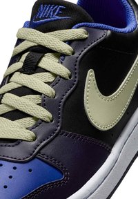 Sneakers Nike con una combinazione di pelle nera e blu navy, lacci verde chiaro e un vistoso swoosh verde chiaro. Dettagli testurizzati e accenti blu.