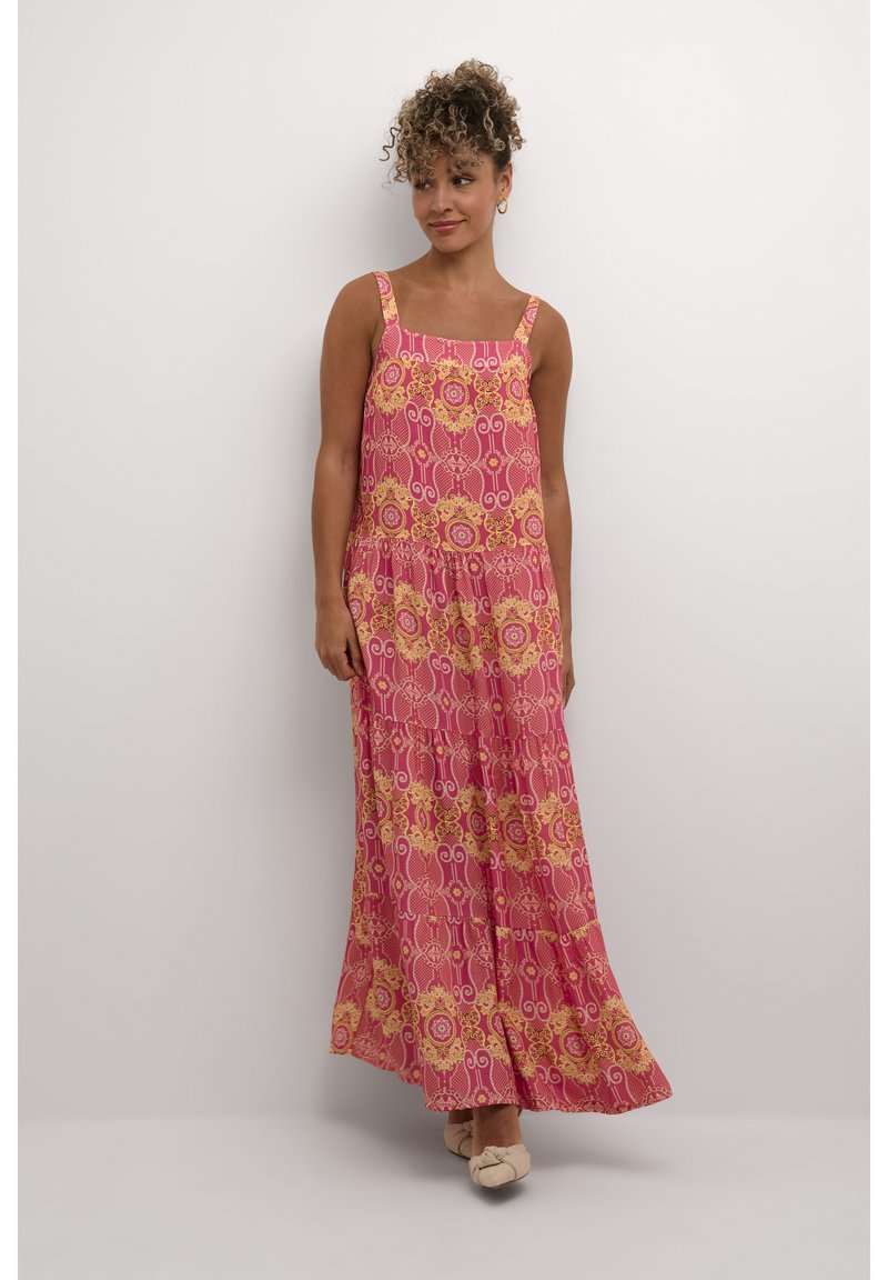 Rosa maxikjol med blommiga och geometriska mönster, med fyrkantiga axelband och en svävande, lager-på-lager design. Mjukt tyg med en lätt textur.