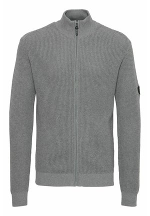Grå strikket cardigan med høy krage, hel frontglidelås, teksturert stoff, ribbestrikkede mansjetter og sidepatch-detalj.