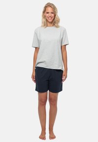 Grijze katoenen t-shirt met korte mouwen, gecombineerd met marineblauwe shorts. De outfit heeft een relaxte pasvorm en een zachte textuur.