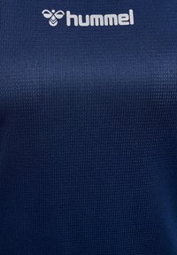 Granatowa koszulka sportowa z teksturowanej tkaniny, z białym logo "hummel" na górze. Prosta, dopasowana forma, idealna do sportu.