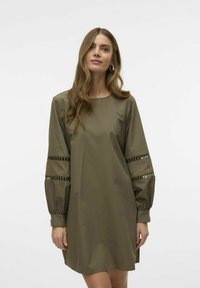 Olivegroene jurk met een rechte snit, voorzien van pofmouwen met decoratieve banduitsparingen en metallic accenten. Glad, lichtgewicht materiaal.