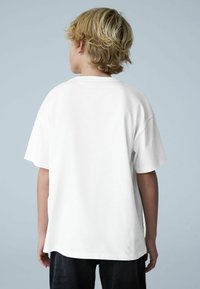 Valge puuvillane t-särk lõdva lõikega, lühikeste varrukatega ja ümmarguse kaelusega. Disainis on ühes tükis seljaosa ja puuduvad mustrid.