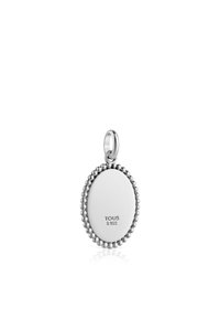 El colgante de plata presenta una forma ovalada con un borde de cuentas, marcado con "TOUS S 925", reflejando una superficie pulida.