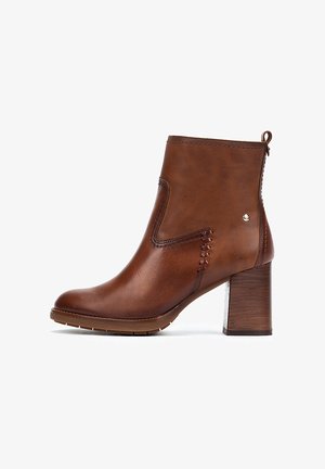 Bottine en cuir marron avec un bout arrondi, des coutures décoratives, un talon épais et une fermeture éclair à l'arrière.