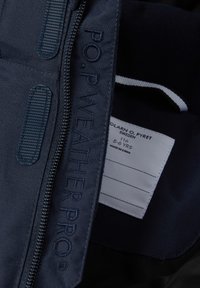 Navy blue weatherproof jacket with textured fabric, zipper closure, and embroidered "P.O.P WEATHERPRO." Care label on the inner side.