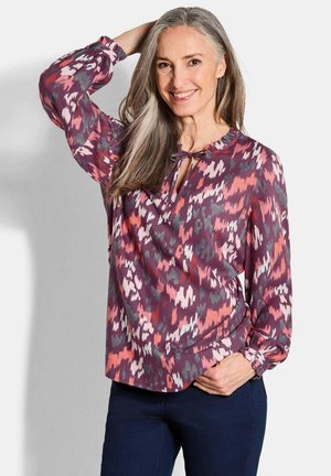 Blusa a maniche lunghe con un motivo astratto viola e rosa, caratterizzata da un collo a chiave con nodo e polsini arricciati, realizzata in tessuto leggero.