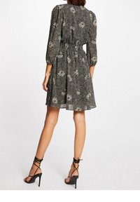 Black and white patterned dress with three-quarter puff sleeves, cinched waist, and a flared skirt. Fabric appears lightweight and textured.