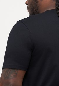 Sort bomulds t-shirt med klassisk rund hals og korte ærmer, der viser en glat tekstur og et enkelt, rent design.