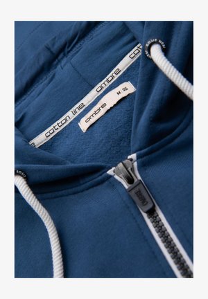 Navyblauwe katoenen hoodie met rits, voorzien van witte trekkoorden en een fleece binnenkant. Zorglabels zijn zichtbaar aan de binnenkant van de kraag.